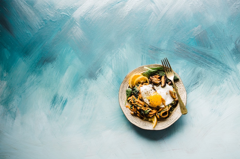 Mesa azul con plato de pasta y vegetales